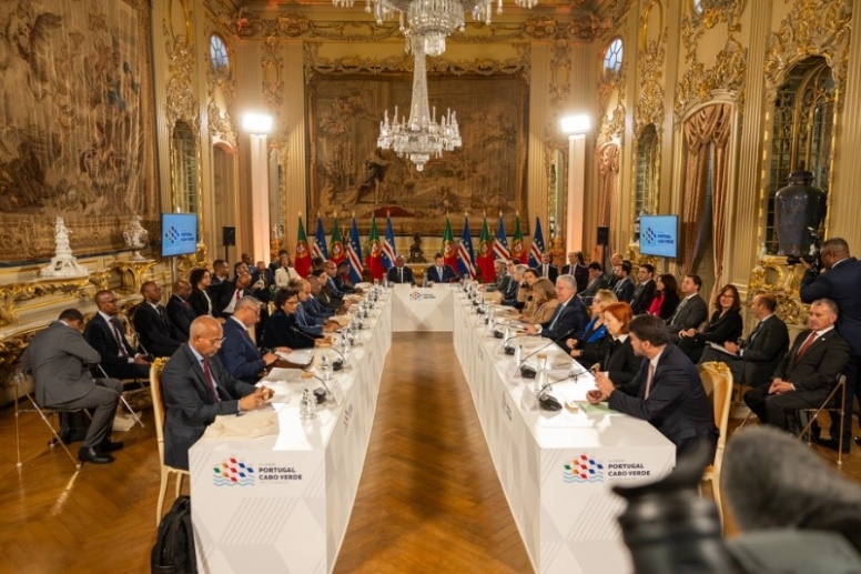 Reunião durante a Cimeira, mesa em U com os participantes sentados e na segunda linha a assistência. Ao fundo várias bandeiras de Portugal e Cabo Verde.