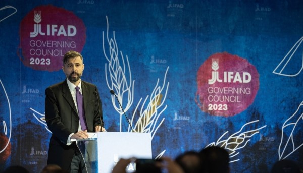 Presidente do FIDA (Alvaro Lario) a discursar. Ao fundo painel em tons de azul com espigas de trigo e logo IFAD Governing Council 2023.