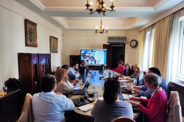 Representantes de Portugal e Grécia reunidos à mesa em sala de reuniões.