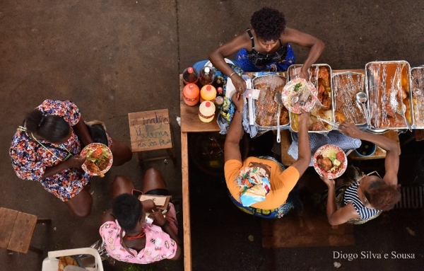 Pessoas a servir comida (vários tabuleiros de comida cobertos com película aderente)