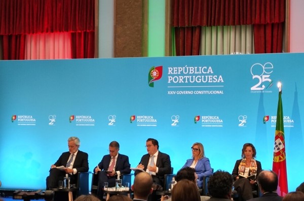 Apresentação do Orçamento do Estado 2025 no Salão Nobre do Ministério das Finanças: Ministro das Finanças (Joaquim Miranda Sarmento) e outros intervenientes sentados em conferência de imprensa. Bandeira Portuguesa do lado direito e painel com logo OE2025 atrás.